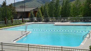 A rectangular swimming pool with a tiled deck, surrounded by a metal fence. - Indian Springs Condo 2423 by Alpine Lodging Sun Valley (Sun Valley)