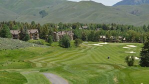 A golf course with a clubhouse, surrounded by rolling hills and trees. - Ranch Condominiums by Alpine Lodging Sun Valley (Sun Valley)