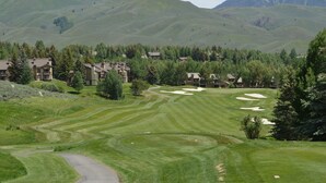 Un parcours de golf avec un club-house et des immeubles résidentiels en arrière-plan.