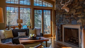 A spacious living room with a stone fireplace, large windows, and a cozy seating area.