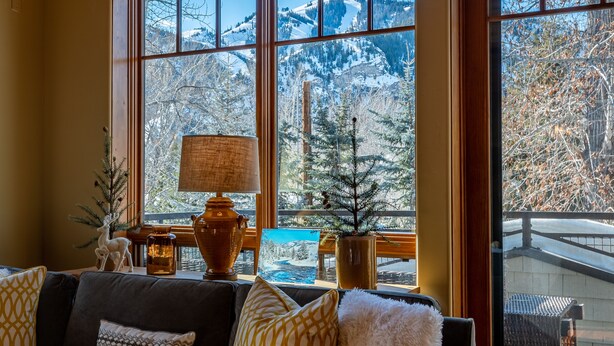 A cozy room with a large window offering a view of snow-covered mountains.