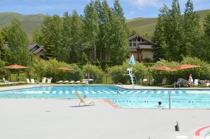 Un espace piscine avec des chaises longues, un plongeoir et une vue sur les montagnes en arrière-plan.