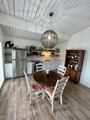 Una cocina con una mesa de comedor, sillas y una lámpara colgante.