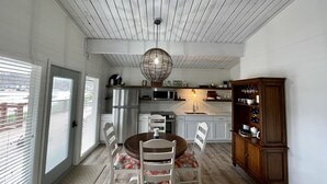 Una cocina compacta con zona de comedor, que presenta un techo de madera, una lámpara colgante y un mueble empotrado.