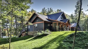 Ein modernes Haus mit Steinfundament, Holzterrasse und einer großen Veranda.