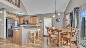A spacious kitchen with wooden cabinets, a refrigerator, a microwave, and a dining area with a wooden table and chairs.