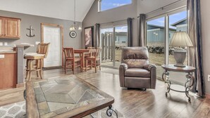 A spacious living room with a fireplace, a dining area with wooden furniture, and a large window offering a view of the outdoors.