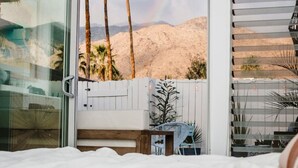A bedroom with a view of a desert landscape, including palm trees and mountains. - Bohemian Mid-Century at the Famed Ocotillo Lodge (Palm Springs)