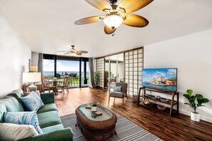 Un salón espacioso con un televisor grande, asientos cómodos y vistas al exterior.