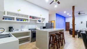 Une cuisine moderne avec des meubles blancs, un îlot central doté de tabourets, une cuisinière et un réfrigérateur.