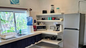 A compact kitchen with a refrigerator, microwave, and sink.