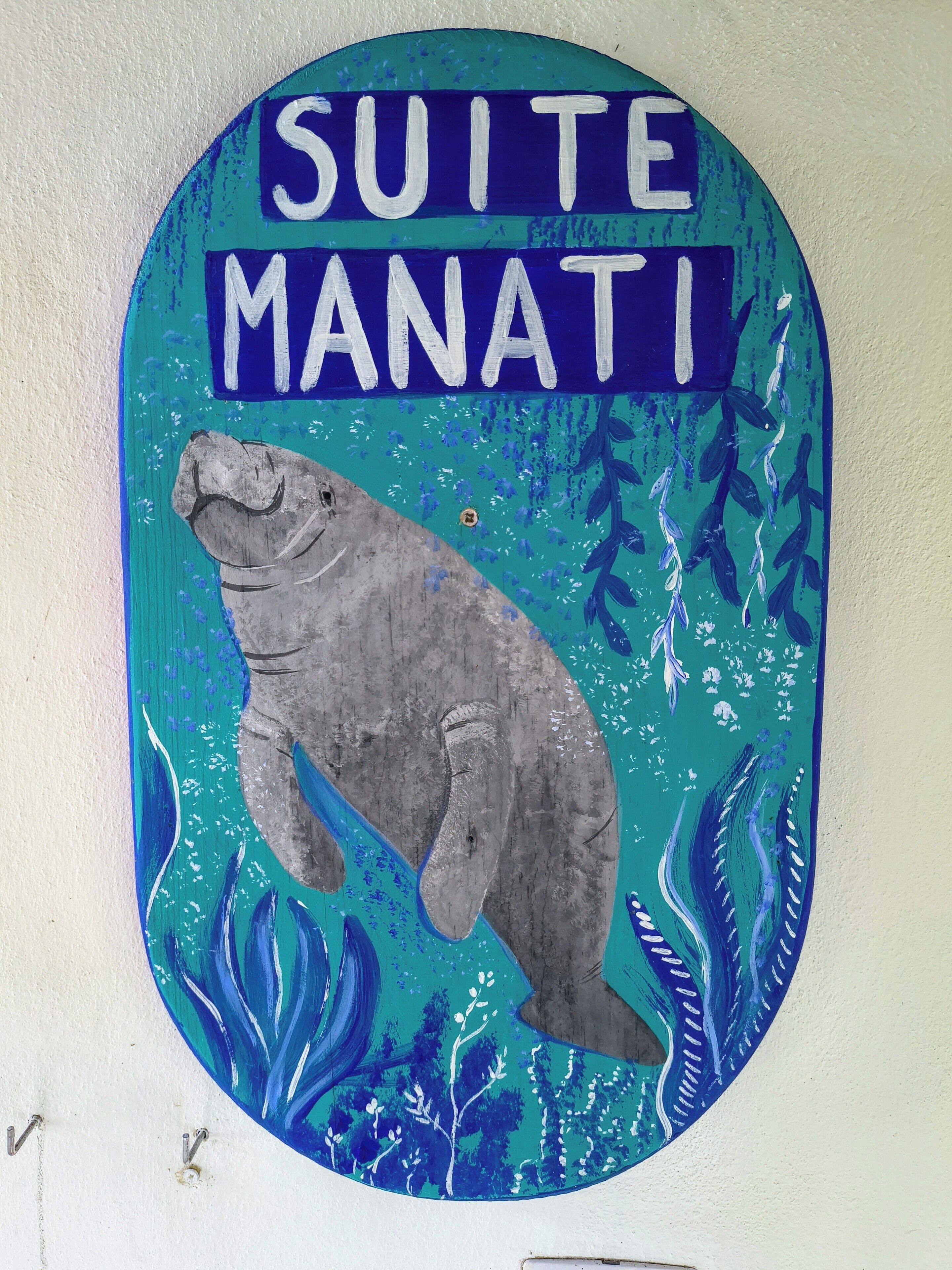 Un letrero en la pared con el texto 'SUITE MANATI' e ilustración de una manatí.