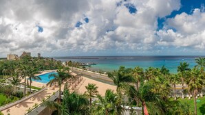 A resort with a pool, palm trees, and a view of the ocean.