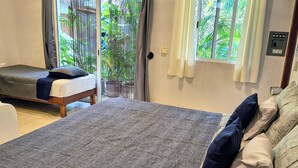 Slaapkamer met een groot bed, een bank, een plafondventilator en uitzicht op het omliggende landschap door een schuifdeur.