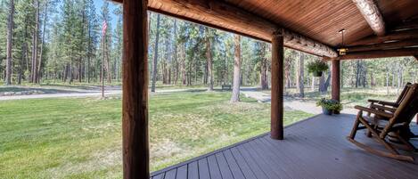 A wooden deck with a rocking chair and a hanging planter.