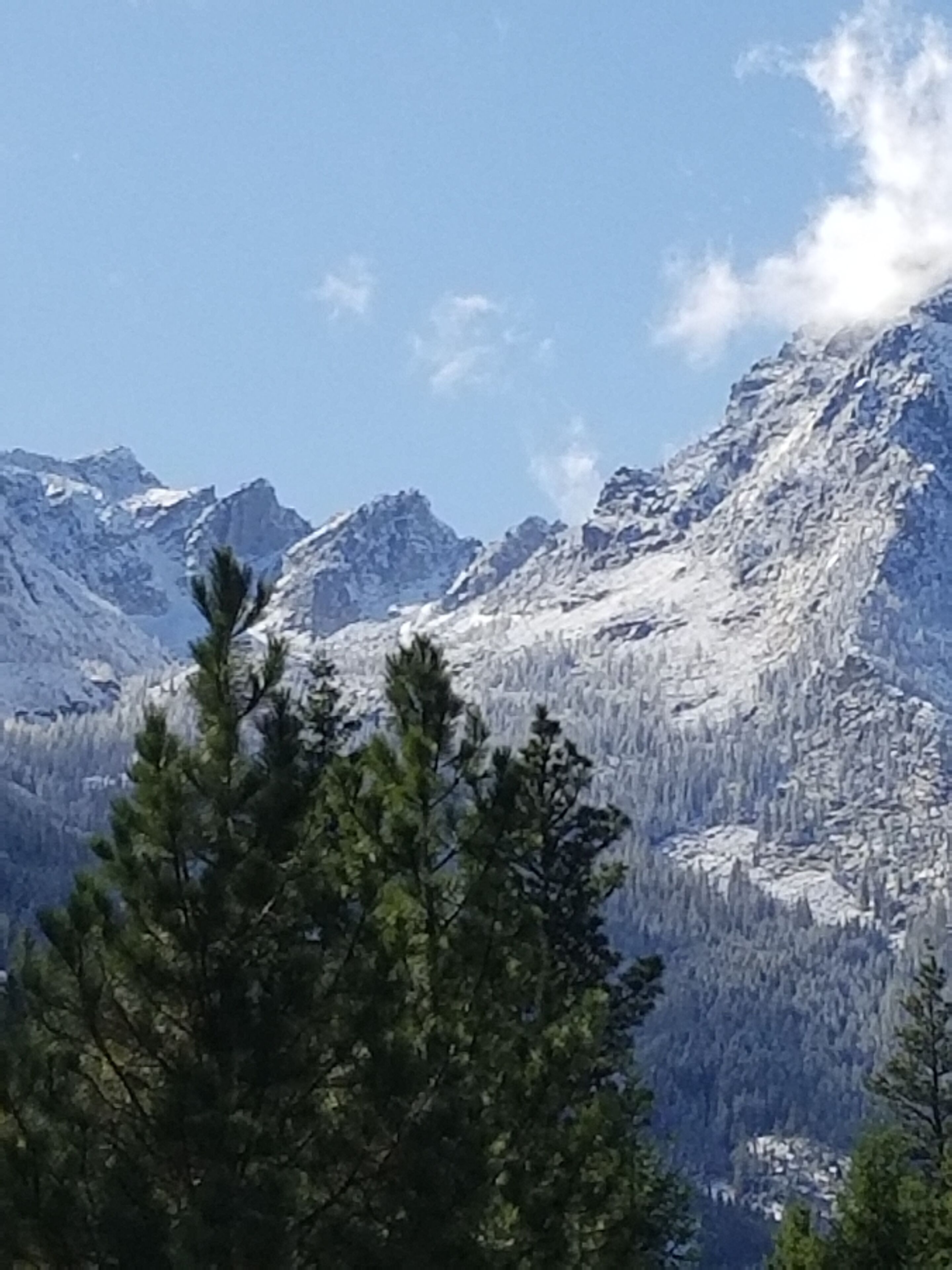 A mountain landscape with snow-covered peaks and dense forest.