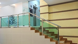 A staircase with glass railings, beige walls, and a green decorative element. - Citi Hotel @KL Sentral (Kuala Lumpur)