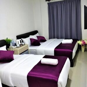 Habitación de hotel con dos camas, una mesita de noche, un hervidor, un teléfono y un jarrón con flores.