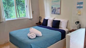 Un dormitorio con cama, ventilador de techo, aire acondicionado, ventana con cortinas y un cuadro en la pared.