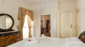 A hotel room with a large bed, a vanity with a mirror, a wardrobe, and a door leading to another room. - Harmony Country House-Live in the Nature (Archanes-Asterousia)