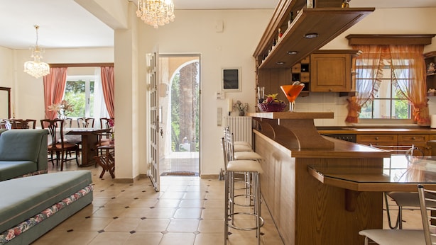 A spacious kitchen with a bar area, wooden cabinets, and a dining area with a sofa and chairs. - Harmony Country House-Live in the Nature (Archanes-Asterousia)