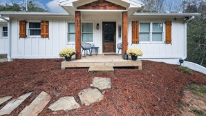 A two-story house with a front porch, stone steps, and a small garden area with potted plants. - Fully Renovated Ranch Home 1/2 mi from Charming downtown Ball Ground (Ball Ground)