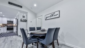 A modern kitchen with white cabinets, a microwave, and a built-in oven. There is a dining area with a round table and four chairs. - Fully Renovated Ranch Home 1/2 mi from Charming downtown Ball Ground (Ball Ground)