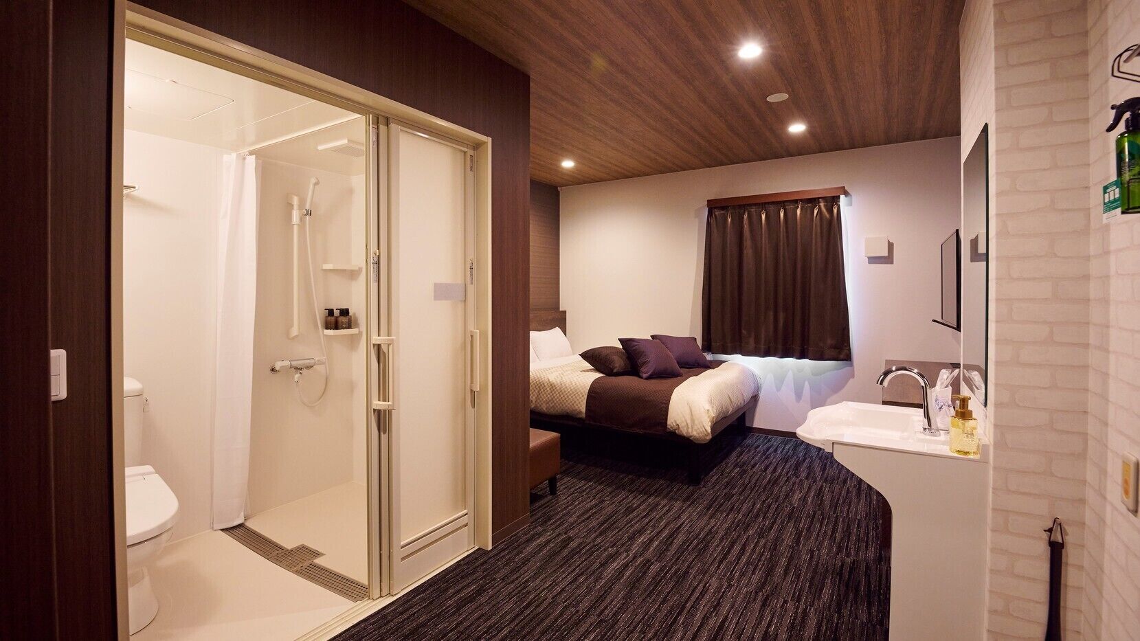 Ein Hotelzimmer mit Dusche, Toilette, Bett und Waschbecken mit Spiegel.