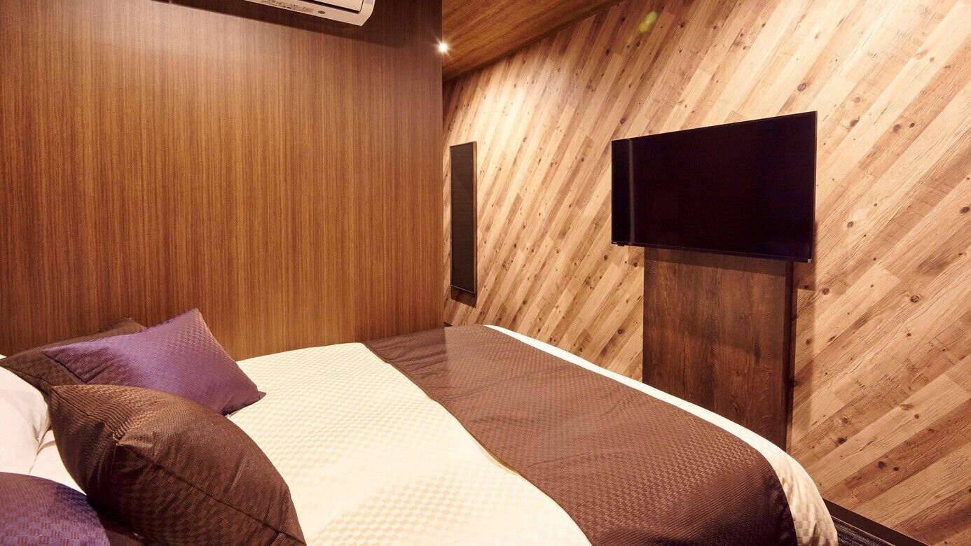 Ein Schlafzimmer mit Bett, Kissen, einem Flachbildfernseher und Holzwänden.