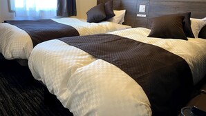 Ein Hotelzimmer mit zwei Betten, jeweils mit einer braun-weiß karierten Tagesdecke, einem Holzkopfstück und einem Fenster mit Vorhängen.