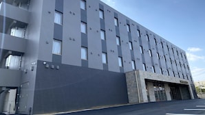 Ein modernes Gebäude mit flacher Fassade, zahlreichen Fenstern und einem Parkplatz davor.