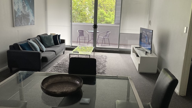 Uma sala de estar moderna com sofá, mesa de centro e televisão.