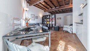 A spacious living area with a glass dining table, a sofa, and a bookshelf. - Studio close by Piazza Navona - A/C - Wi-Fi - Washer (Roma)