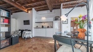 A cozy living area with a dining table, chairs, and a kitchen in the background. - Studio close by Piazza Navona - A/C - Wi-Fi - Washer (Roma)