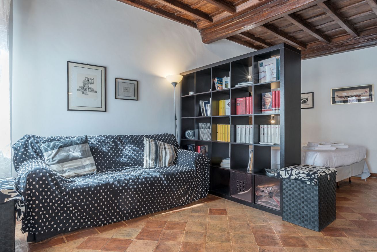 A cozy living room with a patterned sofa, a bookshelf, and a small table.