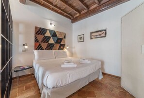 Un dormitorio con una cama, un cuadro de pared geométrico, una fotografía enmarcada y una puerta.