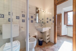 A bathroom with a toilet, bidet, sink, and mirror.