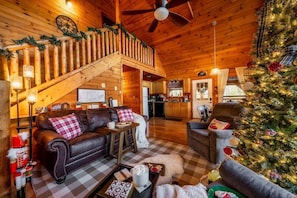 Interior acogedor de una cabaña de madera con chimenea, comedor y un árbol de Navidad.