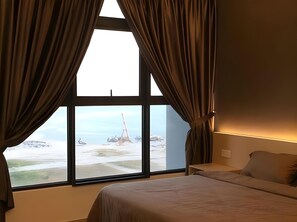 Ein Hotelzimmer mit großem Fenster, einem Bett und einem Nachttisch.