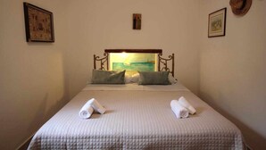 Un letto ben rifatto con copripiumino trapuntato, due cuscini e due asciugamani arrotolati.