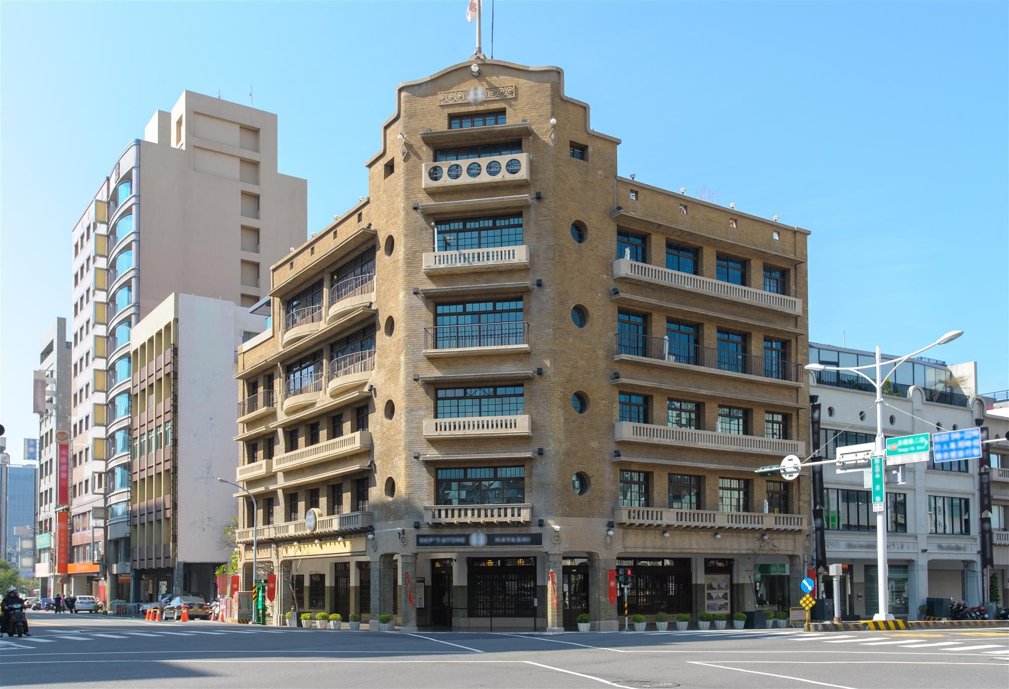 A multi-story building with a central entrance, large windows, and balconies.