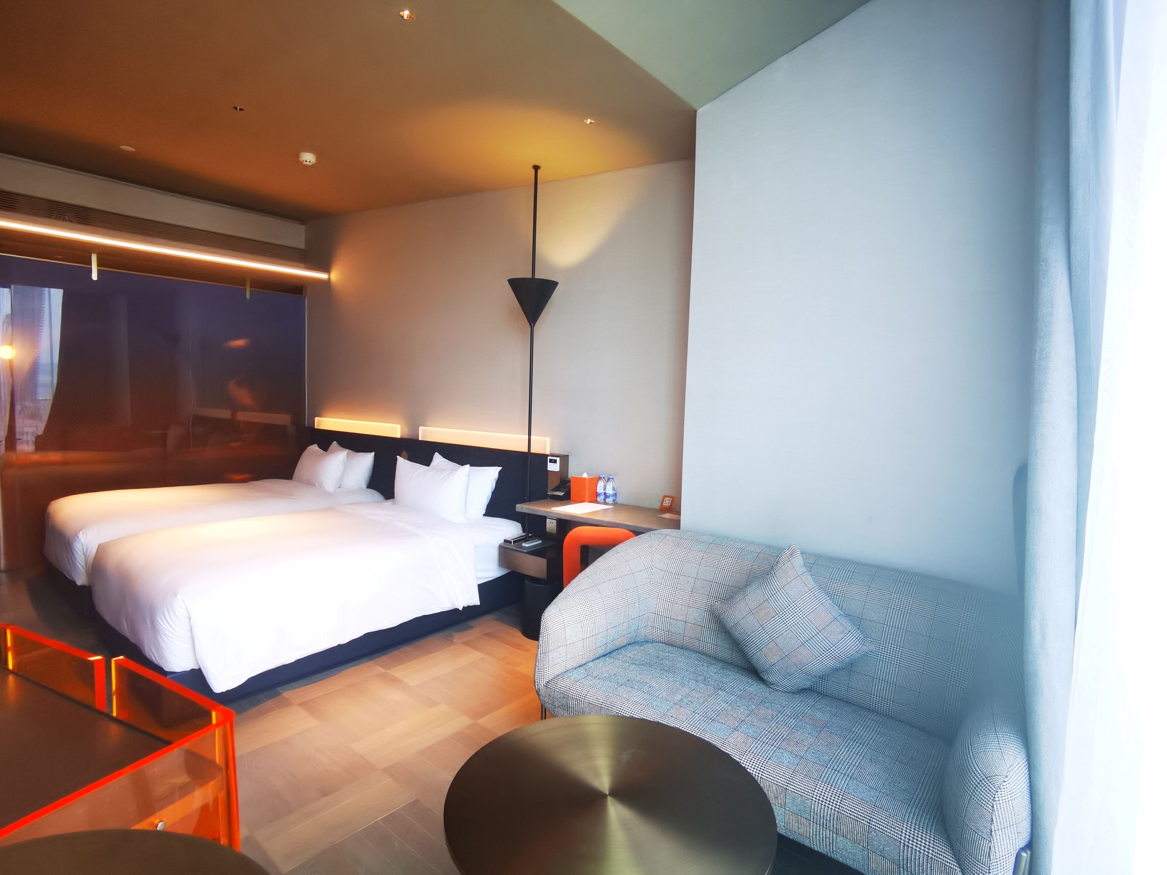 Una habitación de hotel con dos camas, un sofá, una mesa y una lámpara.