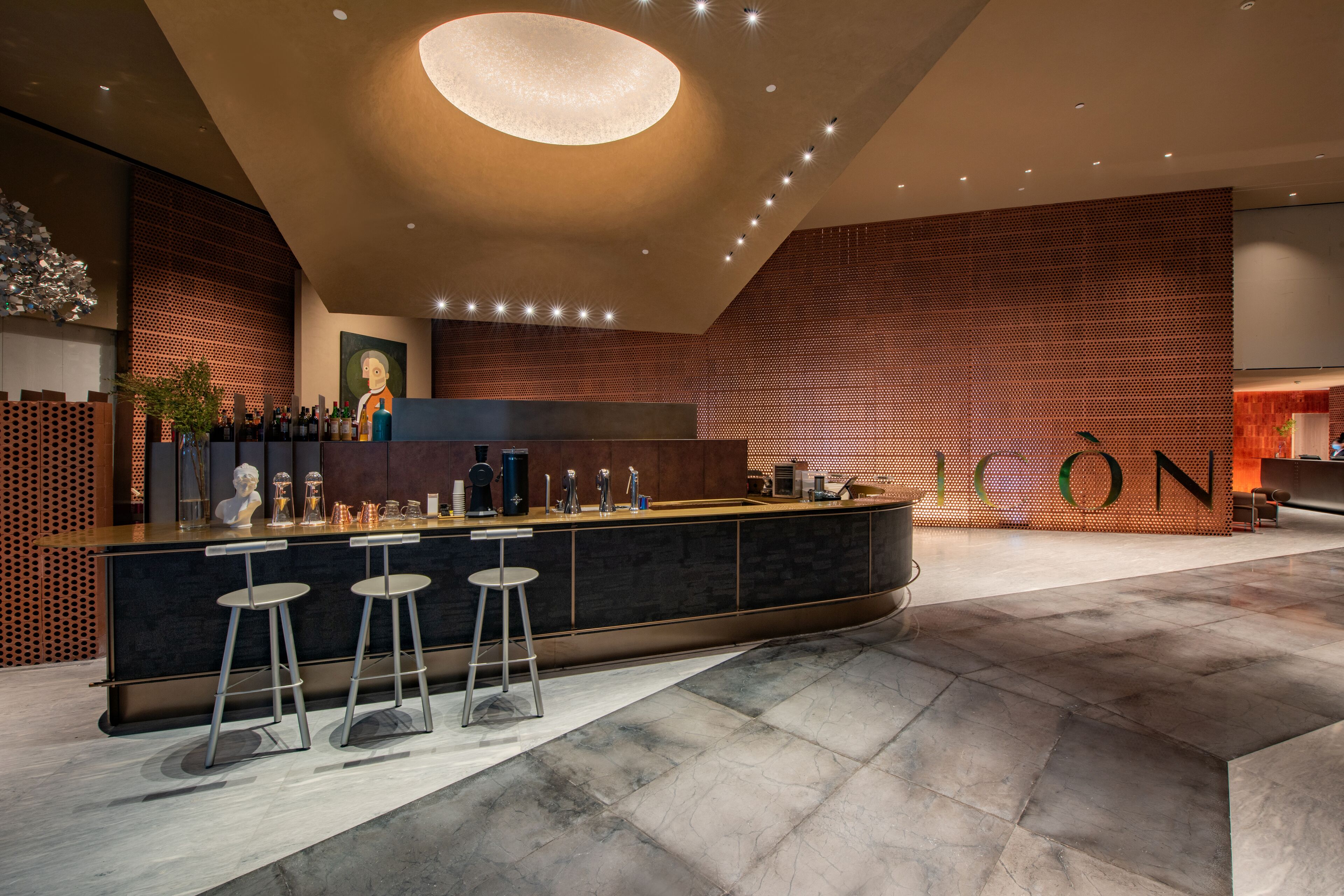 En moderne bar med en central disk, barstole og et stort, oplyst loft.
