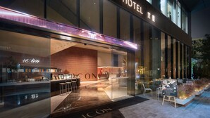Een modern hotelgebouw met een glazen gevel, een receptie en terras.