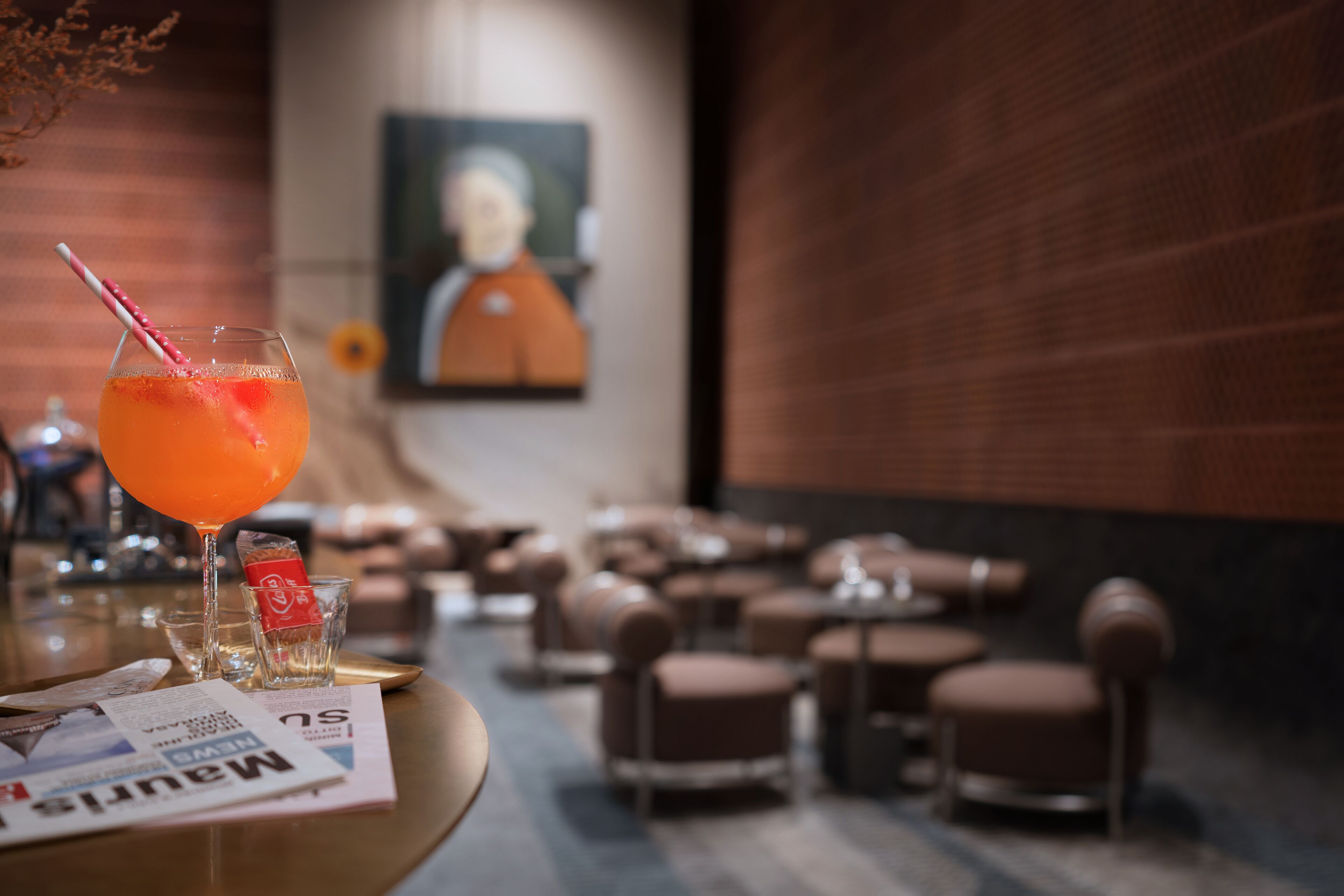 Een bar met een drankje, een menukaart en een schilderij op de achtergrond.