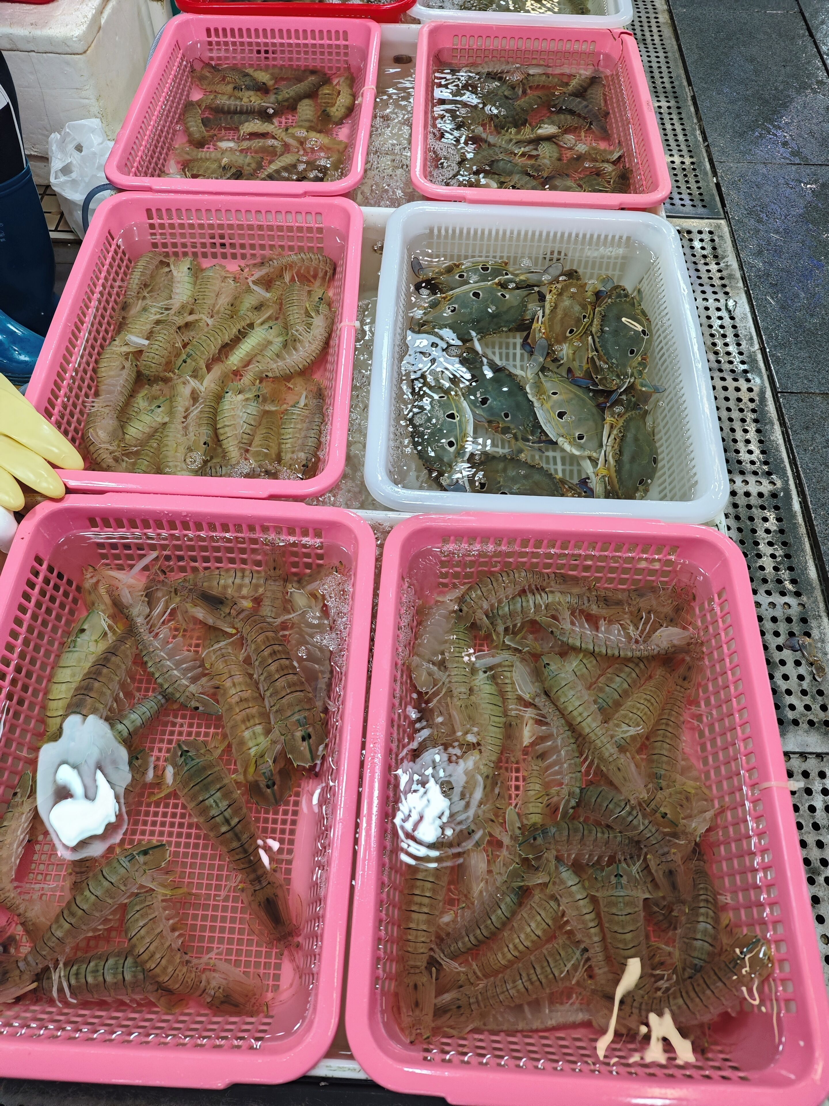 A table with multiple pink and white plastic baskets containing seafood.