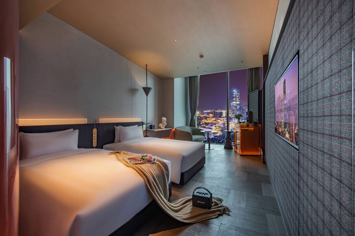 Habitación de hotel moderna con una cama grande, un sofá, un escritorio y vistas a la ciudad.