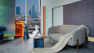 A modern living room with a city view, a sofa, a coffee table, and a statue.