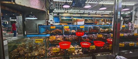 A seafood market with various seafood displayed in glass cases and red bins, with price tags visible.