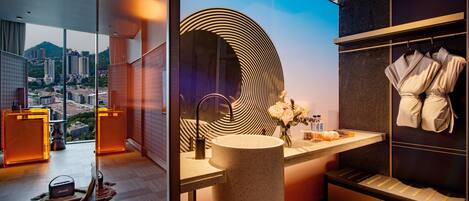A modern bathroom with a large mirror, a sink, and a vanity. There is a view of a cityscape through large windows.